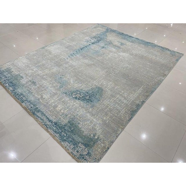 This gray wool rug features a hand knotted pile construction and originates from India. It embodies a modern and...