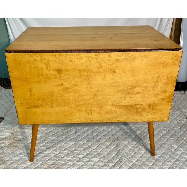 This iconic Mid-Century Modern solid maple drop-leaf dining table is designed by Paul McCobb for the legendary Planner...