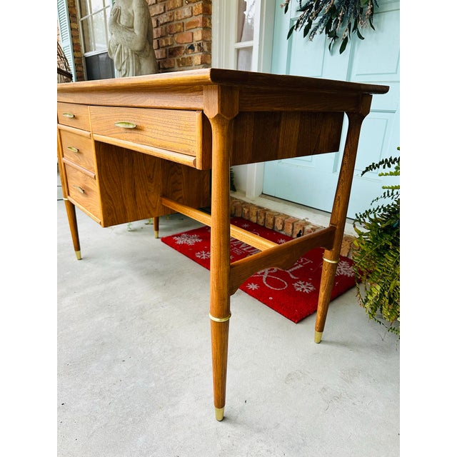 mid-century walnut writing desk. Features two pencil drawers and a larger file drawer, brass accents, and solid sculptural...