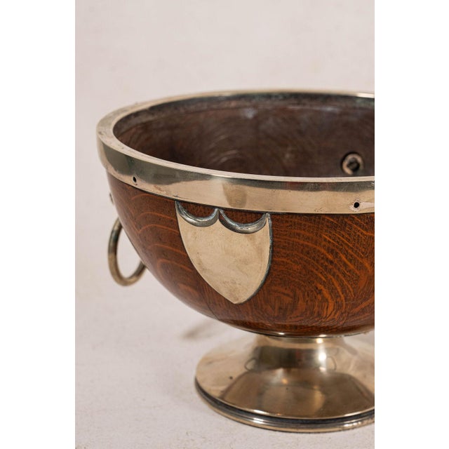 19th-century pedestal bowl featuring an oak body, silver-plated rim, and lion head handles.