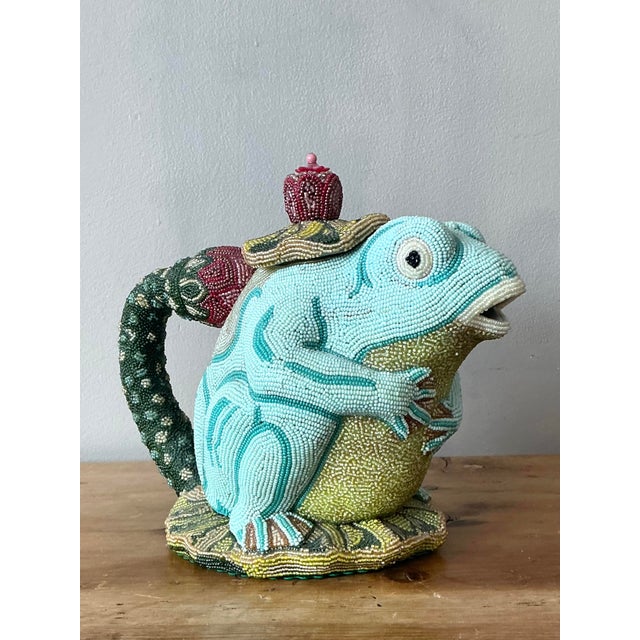 Discover the whimsical artistry of "The Prince Frog," a stunning hand-beaded figurative teapot that serves as a...
