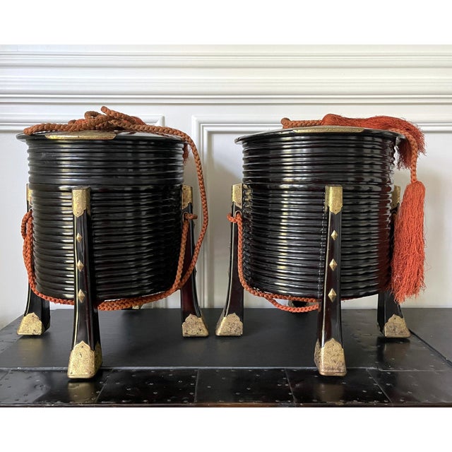 A pair of Japanese lacquered lidded Hokai boxes with chased brass hardware and original ropes. Hokai boxes are...
