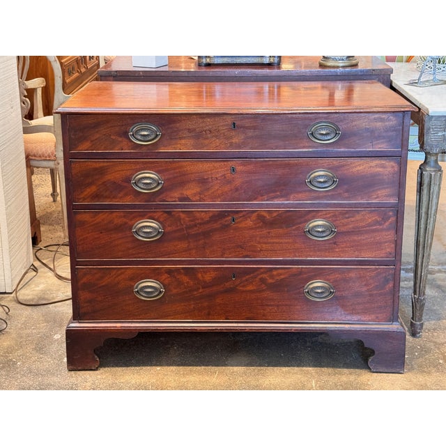 Late 18th to early 19th century George III mahogany chest featuring four graduated drawers, each with brass oval backplate...
