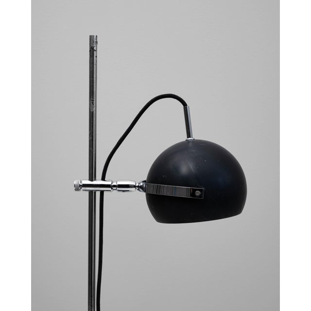 A striking example of mid-century French design, this adjustable metal table lamp features a sleek black domed shade...