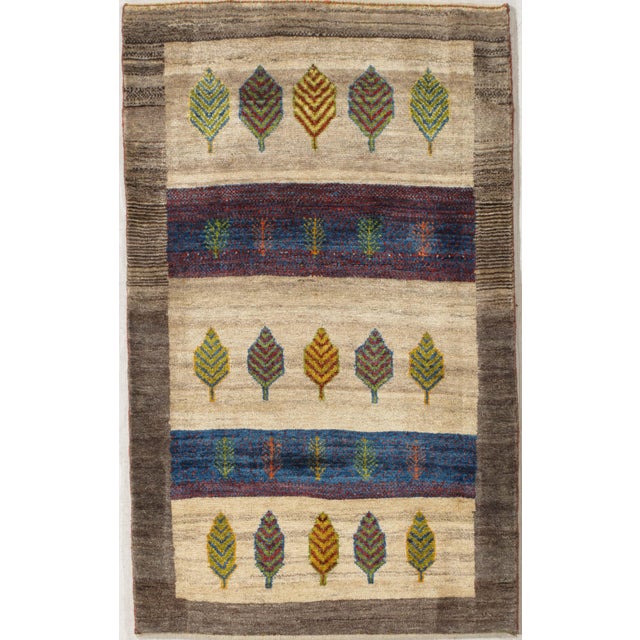 Hand-knotted Persian Gabbeh wool rug featuring rows of stylized leaf motifs on an ivory field, with horizontal bands of...