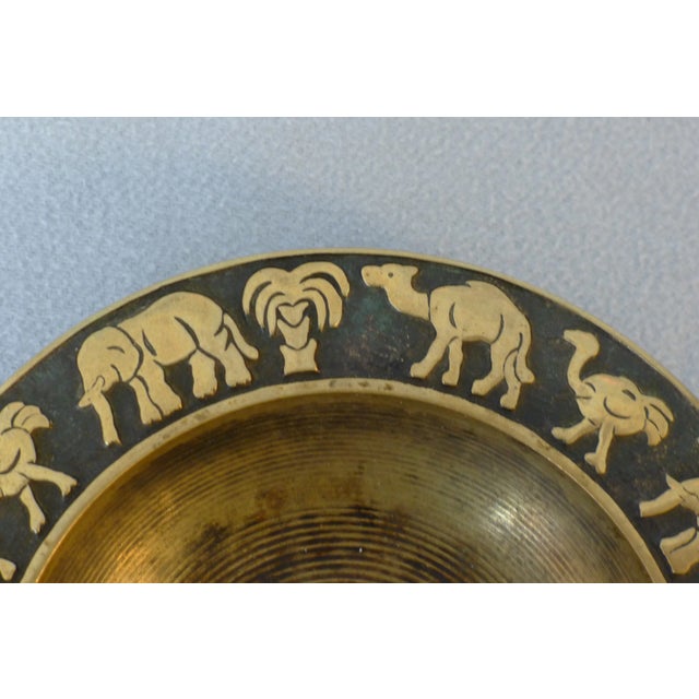 Ashtray of bronzed brass. Circulating relief with representations of elephant, ostrich, camel and palm tree, and the...