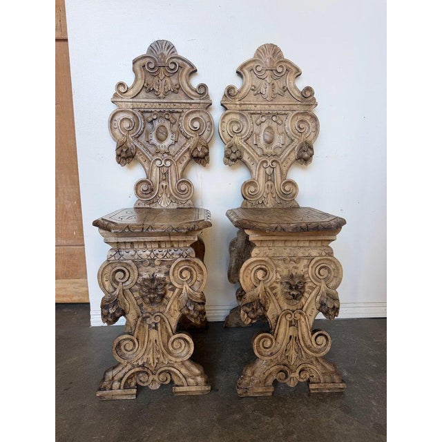 A truly exceptional pair of Italian Renaissance Revival hall chairs, masterfully hand-carved from solid walnut in the...