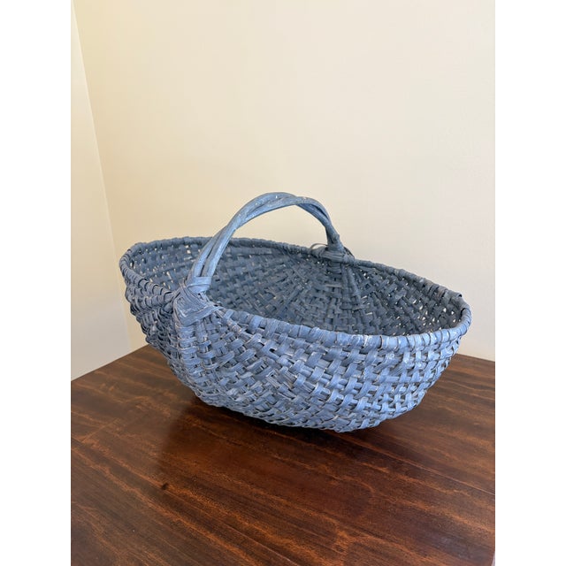 A large American splint oak gathering basket with woven twig handle, painted in a gorgeous pale blue. The charming basket...