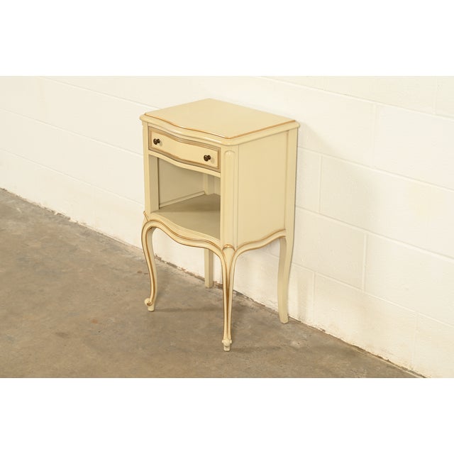 A gorgeous French Provincial Louis XV style one-drawer nightstand By Drexel USA, Circa 1950s Cream lacquered walnut, with...
