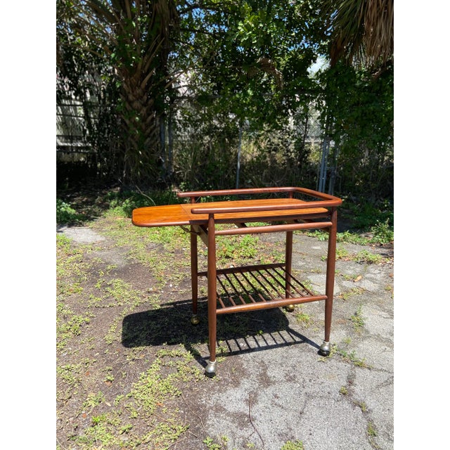 Mid century modern drop-leaf rolling bar and service cart in the style of Arthur Umanoff. Beautiful grain detail and...
