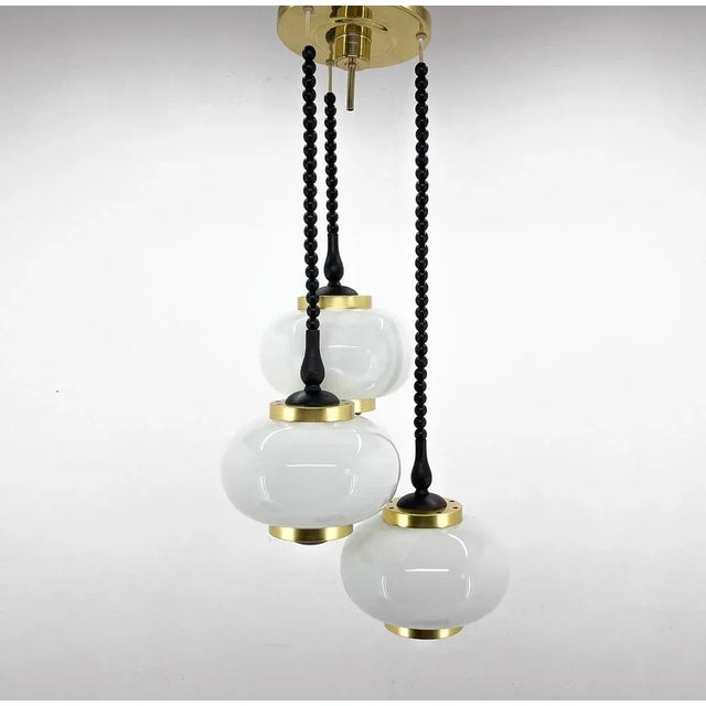 Vintage chandelier made in Poland in the 1970's by Polam Bielsko. Made of brass, metal, wood and milk glass. This piece is...