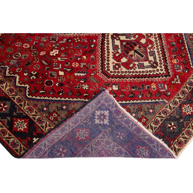 Beautiful vintage Persian Shiraz hand-knotted wool rug with a red color field. This piece has a navy blue frame and...