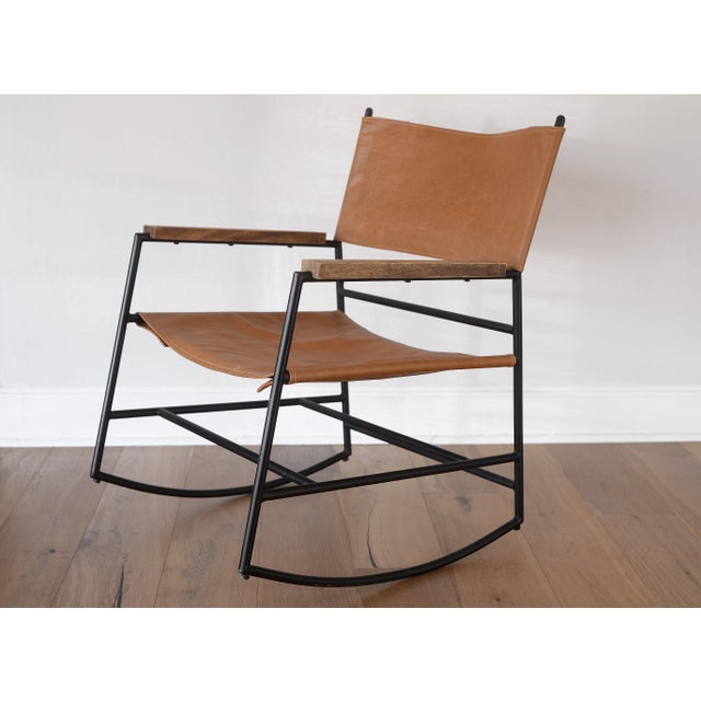 Unique mid century modern style contemporary rocking chair with a black metal frame. The seat and back are made of faux...