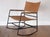 Unique mid century modern style contemporary rocking chair with a black metal frame. The seat and back are made of faux...