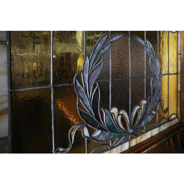 Antique c. 1900 stained glass window in wooden encasement. This lovely window has a slag glass border in tones of amber...