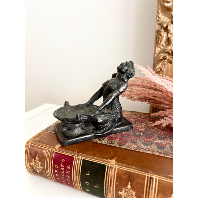 Featuring a striking kneeling figure, this cast metal piece embodies the allure of ancient Egypt, a popular design...