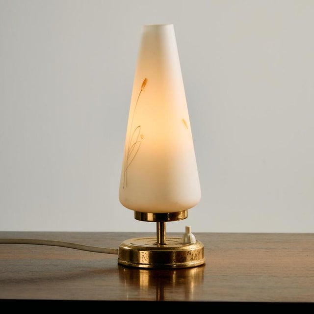 A tiny and charming piece. Austrian brass and glass table lamp from the 1950s, designed by Rupert Nikoll. Its surface...