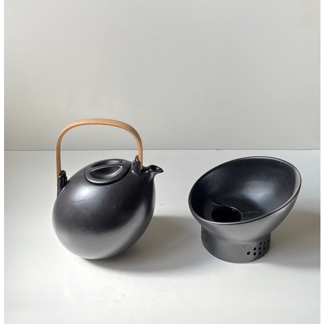 Black teapot and stand/warmer in glazed ceramics. Stylish organically shaped teapot in an ovoid form and with a practical...
