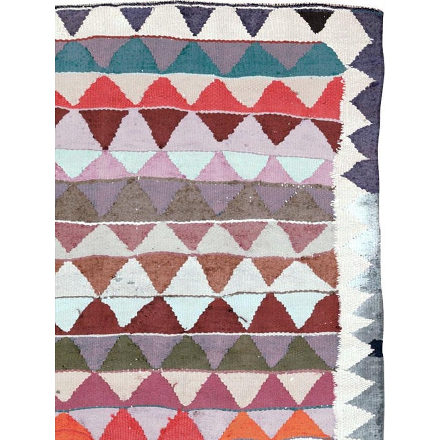 A Mid-20th century Persian flatweave kilim featuring an engaging field of rhythmic, horizontal bands composed of repeating...