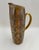 A beautifully textured “Seta” pitcher by Aldo Londi for Bitossi, featuring layered bands of warm metallic tones and...