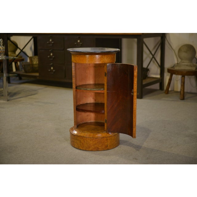 A round Biedermeier-style column/bedside table, circa 1825–1845, with an elegant cylindrical shaft veneered in birch or...