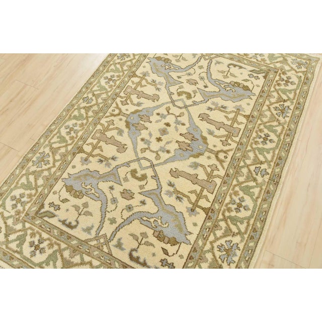 A modern tribal Oushak rug hand-knotted with an all-wool pile on a cotton foundation. This oriental rug features a central...