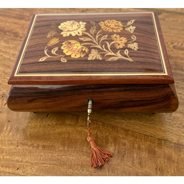 This rare vintage Italian Sorrento lacquered box with lovely floral marquetry inlaid detail is velvet lined and plays...