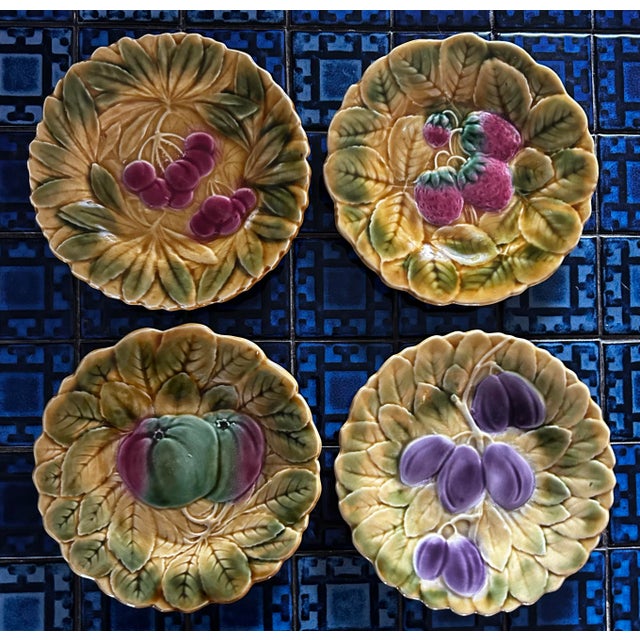Set of four vintage French majolica fruit plates by de Sarreguemines. Measuring 7.5” across, each plate depicts a...