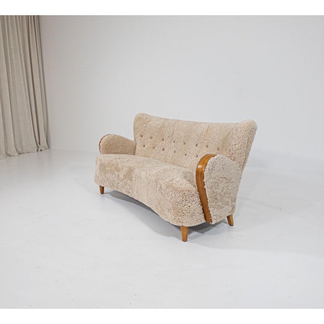 A beautifully sculptural Swedish Modern sofa from the 1930s–40s, newly upholstered in luxurious natural sheepskin. The...