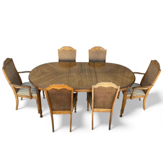 A refined late 20th-century dining suite featuring an oval pedestal table and six high-back chairs. Crafted from warm,...