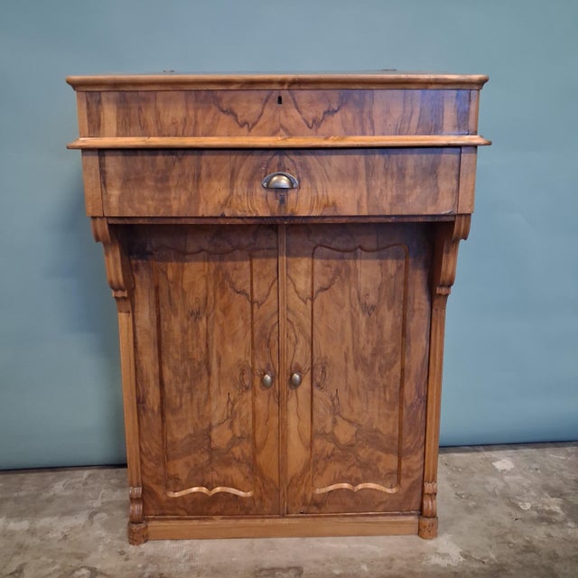 Period: Biedermeier, circa 1840 Material: Walnut veneer, softwood carcass Writing surface: Leather-inlaid flap top...