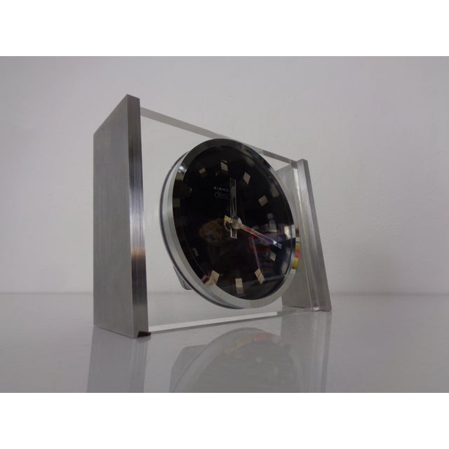 A Kienzle table clock from the 1960s, crafted from acrylic glass and brushed aluminum. The clock comes in its original box...