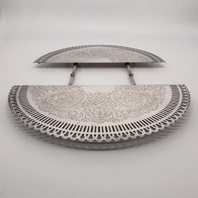 An elegant early 20th-century expanding trivet by Weidlich Brothers Manufacturing Company, featuring ornate engraved...