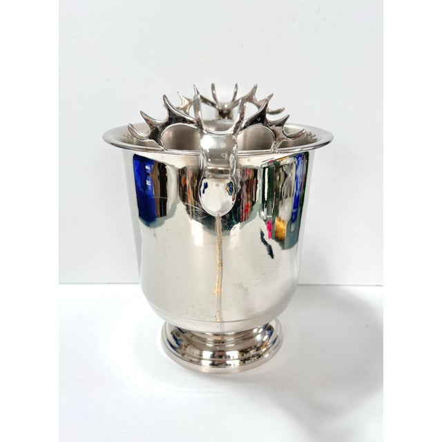 A substantial vintage silverplate ice bucket with sculptural stag-head handles and a bright reflective finish. Measuring...