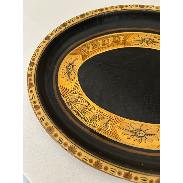 Stylish mid-century oval metal tray featuring a hand-painted ornate motif with burnished gold accents on a faux leather...