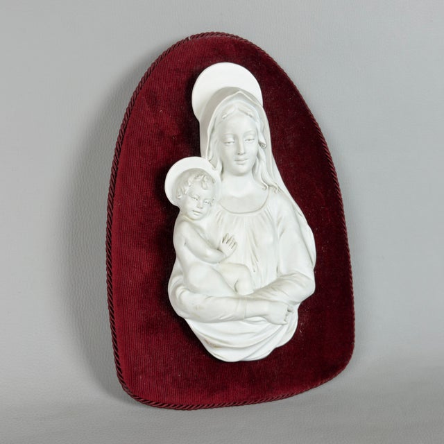 A delicate devotional bas-relief wall sculpture depicting the Madonna and Child, crafted from the finest biscuit porcelain...