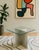 Mid Century Modern side table featuring an intersecting chrome base topped with a thick, green-edge glass surface....