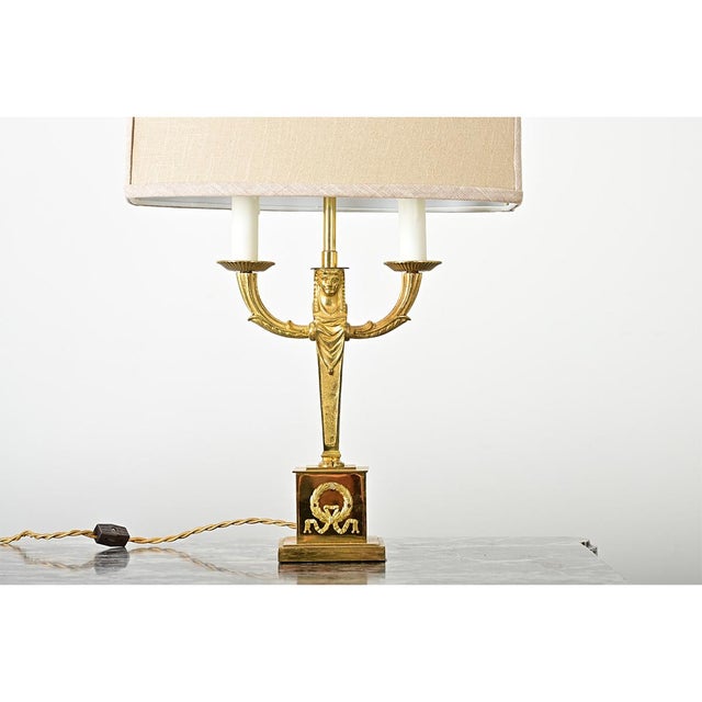French vintage (early 20th century) Empire-style cast brass table lamp with custom linen shade. This striking fixture...