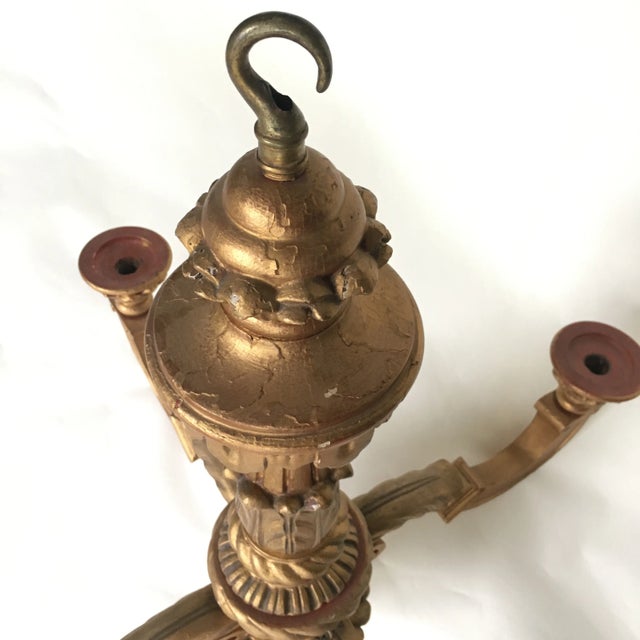 A lovely antique 19th century European gold giltwood 4-arm chandelier with beautifully carved detail. Centered on a...