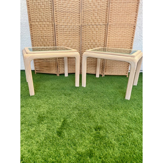 A beautiful pair of vintage rattan waterfall side tables with glass top inserts. These timeless tables have a clean...