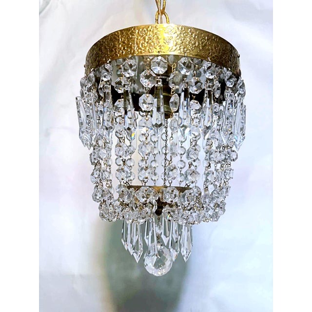 This ornate hanging chandelier features a richly textured gold-toned metal frame with detailed patterning along the rim....
