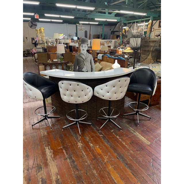 A dramatic Hollywood Regency bar ensemble featuring a sculptural serpentine white laminate top, dark wood veneer base, and...