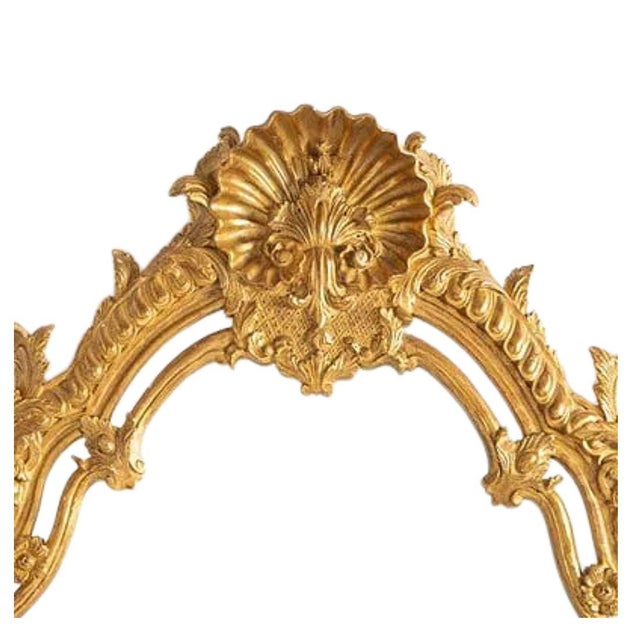 A giltwood pier mirror featuring an elaborately carved frame with scrolling foliate decoration, shell motifs, and a...