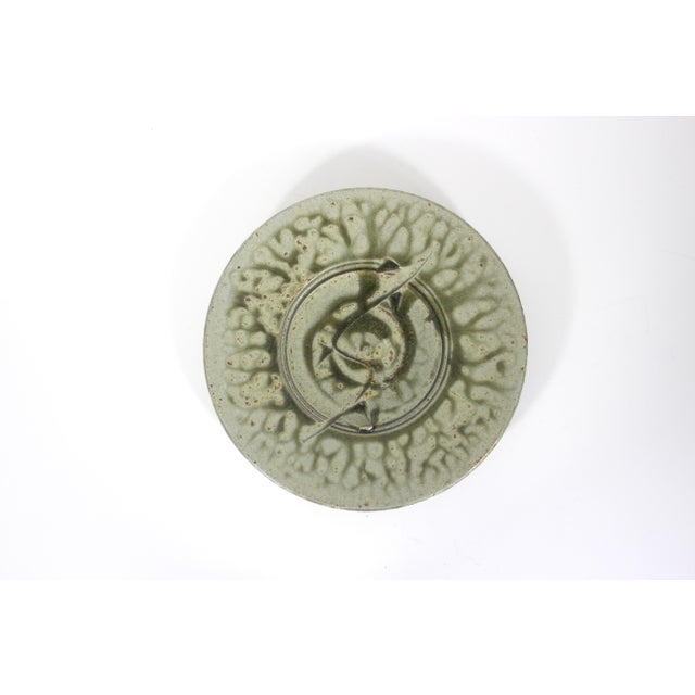 Vintage, textured, earthy green studio pottery plate with a carved detail. Has a wire on the back to hang on the wall....