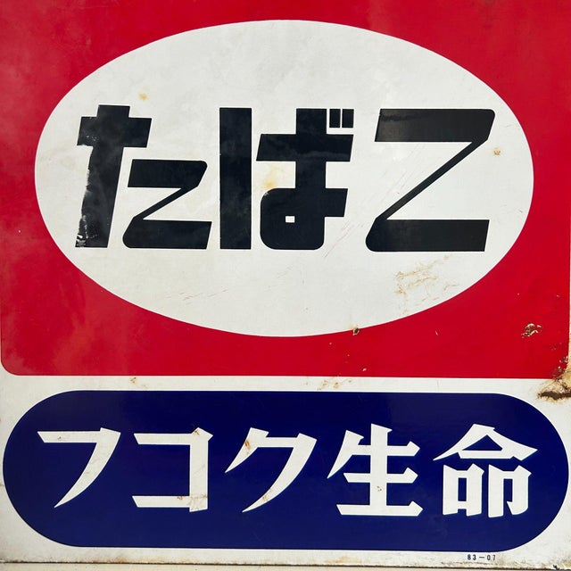 Bold, graphic vintage enamel sign: the top panel reads たばこ (“tabako” – tobacco) in black within a white oval on a red...
