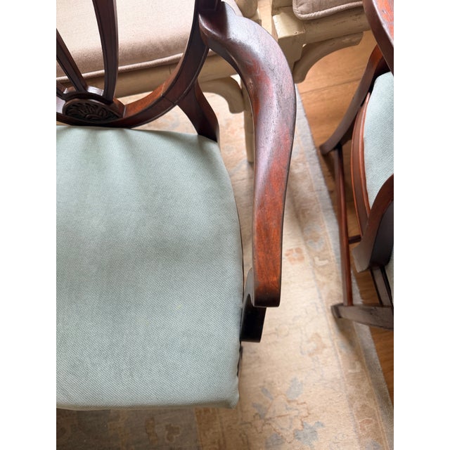 A rare set of four vintage Hepplewhite shield-back armchairs featuring carved wheat sheaf details and rich mahogany...