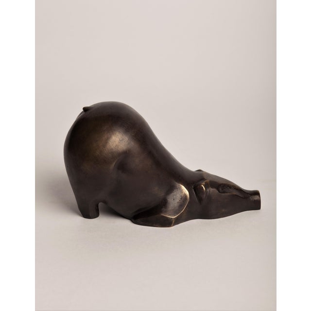 An Art Deco–style animal bronze of a pig, its body pared down to a single rounded, swelling volume that tapers to a...