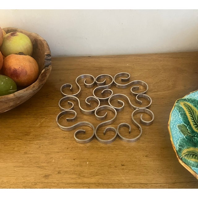 Christofle arabesque scrolling trivet set of three made in France in the 1960's. Small trivets 5.6" Large trivet 9.4"