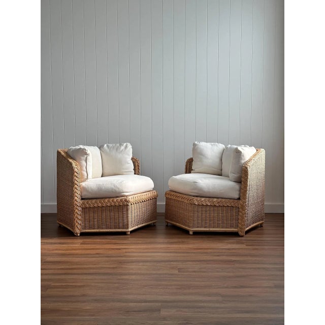 This vintage pair of lounge chairs is handwoven from braided rattan, with low, architectural profiles and a warm honey...