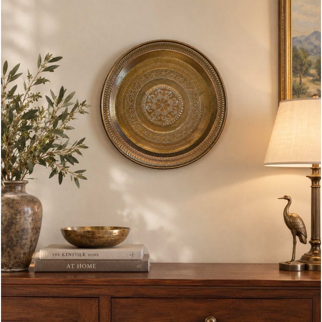 Add warmth and vintage character to your home with this decorative brass wall platter, measuring approximately 22 inches...